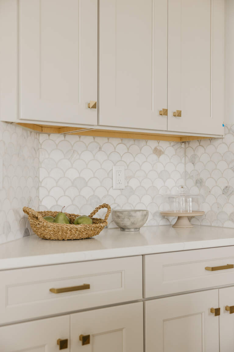 a white kitchen counter with white cabinets and a basket of fruit